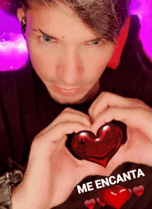 a man is making a heart shape with his hands with the words me encanta written below him