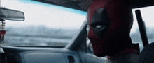 deadpool is sitting in the back seat of a car .