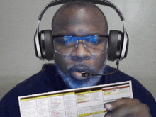 a man wearing headphones and glasses is holding a paper