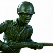 a green toy soldier with a helmet is holding a gun .