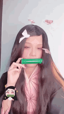 a girl with long hair is wearing a kimono and holding a green object in her mouth