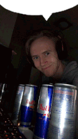 a man wearing headphones stands next to two cans of red bull energy drink