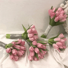 three bouquets of pink tulips are on a white cloth