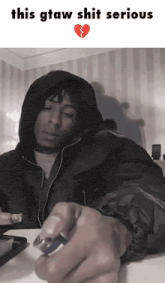 a man in a hooded jacket is holding a lighter with a broken heart behind him