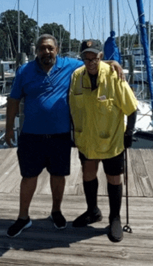 two men are posing for a picture on a wooden dock