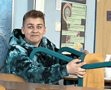 a boy in a classroom with a poster on the wall that says ' a.c. '