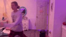 a girl is dancing in a room with purple lights on the walls .