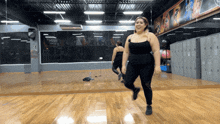 a woman stands in front of a mirror in a gym with a sign on the wall that says ' mizuno '