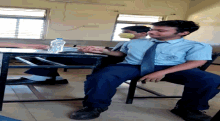 a boy in a school uniform is sitting at a desk with a bottle of water in front of him