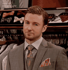 a man in a suit and tie is standing in front of a closet filled with shirts and ties .