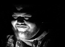 a black and white photo of a man with a beard in the dark