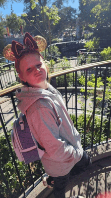 a little girl wearing minnie mouse ears and a purple backpack