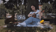 a woman sits under a tree playing a guitar with a book titled " i 'm the girl " in the background