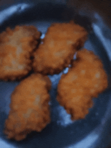 four pieces of fried food on a plate with a blue background