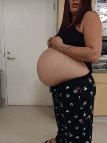 a pregnant woman with a tattoo on her arm holds her belly