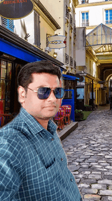 a man wearing sunglasses is standing in front of a restaurant sign