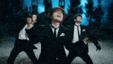 a man in a suit and tie is dancing in front of two other men