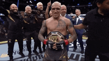 a man with a ufc belt around his waist is surrounded by other men
