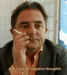 a man in a suit is smoking a cigarette and saying `` all i have are negative thoughts '' .