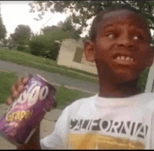 a young boy wearing a california shirt is holding a bag of chips .