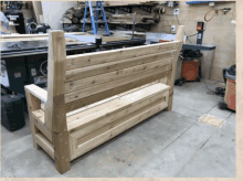 a wooden bench is sitting in a garage next to a vacuum cleaner .