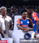 a man in an india jersey shakes hands with a man in an orange shirt