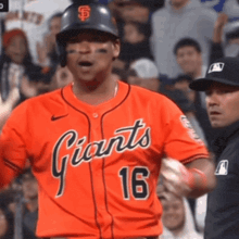 a baseball player wearing an orange jersey with the number 16 on it