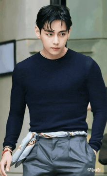 a man wearing a black sweater and grey pants is walking