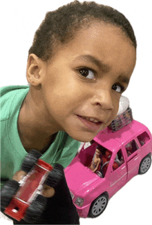 a young boy in a green shirt is holding a toy car in his hand