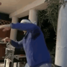 a man in a blue hoodie is dancing in front of a grill .