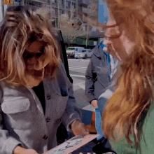 a woman in a grey jacket is holding a piece of paper that says ' i love you ' on it