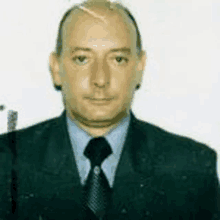 a man wearing a suit and tie is standing in front of a white background .