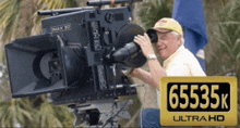 a man taking a picture with a camera that says 6535k ultra hd