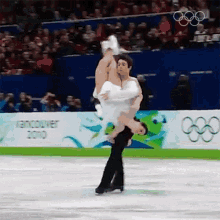 a man is carrying a woman on his shoulders while ice skating in front of a banner that says vancouver 2010