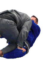 a man in a gray jacket is wrestling another man in a blue shirt