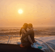 a man and a woman are sitting on the back of a boat in the ocean at sunset