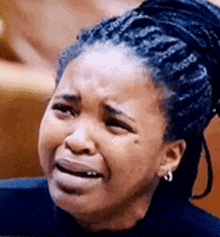 a woman with braids is crying with her eyes closed and her mouth open .