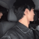 a man wearing a black leather jacket is sitting in the back seat of a car