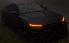 a black car with the headlights on is parked in the dark