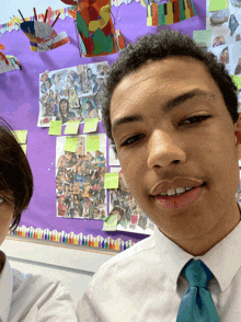 two boys pose for a photo in front of a bulletin board