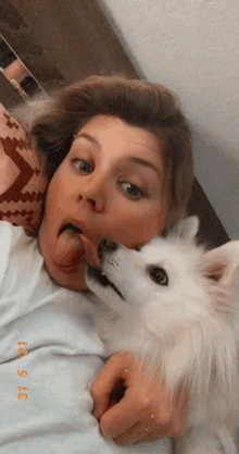 a woman sticking her tongue out while holding a white dog