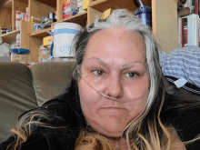 a woman wearing an oxygen mask is sitting in front of a shelf with a cup that says ' iced tea '