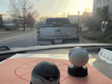 a ford truck is parked on the side of the road behind two small balls