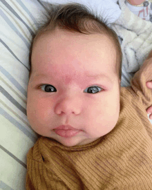 a close up of a baby 's face with a striped pillow in the background