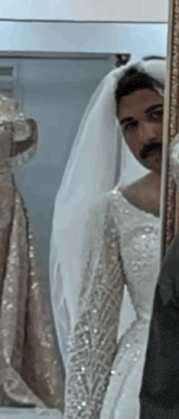 a man in a bride 's dress is looking at himself in the mirror