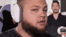 a man with a beard wearing headphones and a nose ring is sitting in a chair .