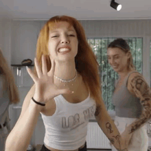 a woman with red hair is wearing a white tank top that says love