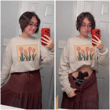 a woman taking a picture of herself in a mirror while wearing a sweater with flowers on it