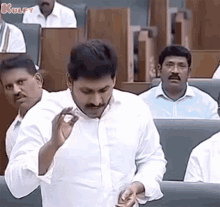 a man in a white shirt is holding a piece of paper in his hand while sitting in a parliament .