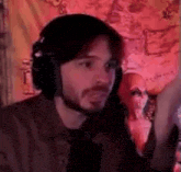 a man wearing headphones is standing in front of a microphone in a dark room .